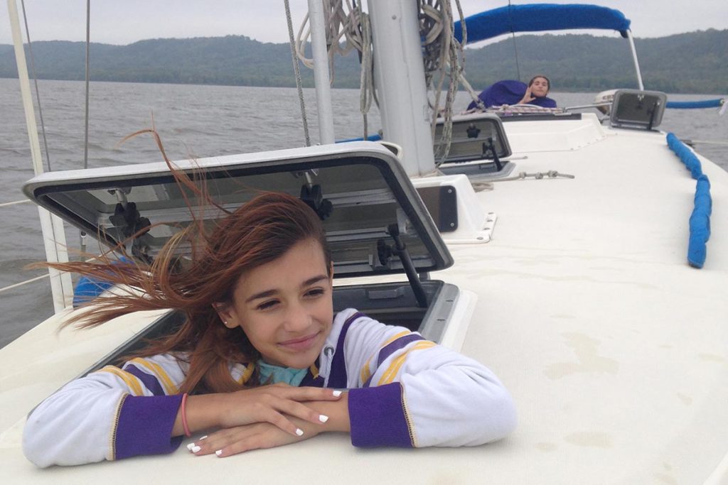 a young person on a sailboat with the wind in her hair