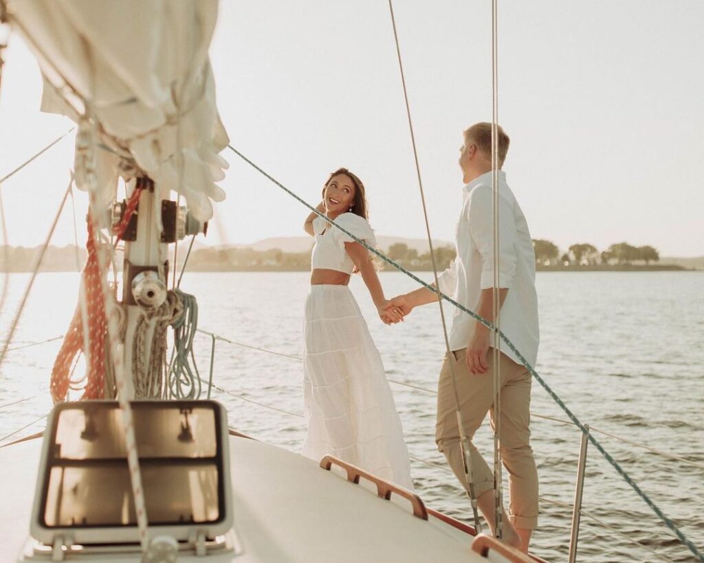 Couple onboard a sailboat taking engagement photos on Lake Pepin during the summer.
